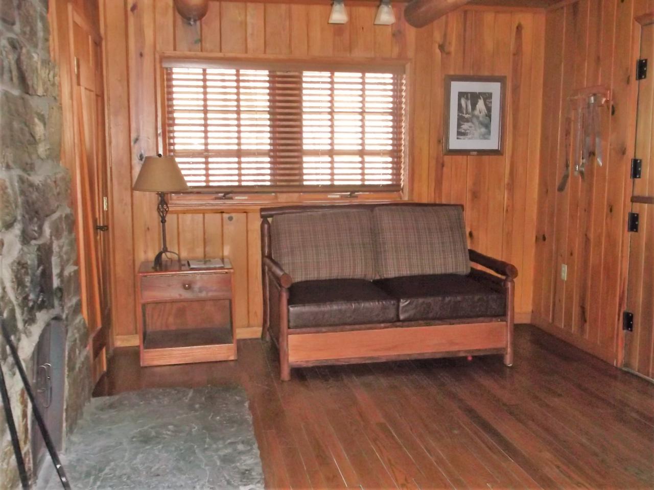 A view of the living room in cabin 15 including a couch, fireplace, and exterior window